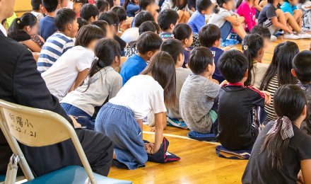 防災頭巾を使って胸骨圧迫の練習をする児童たちのイメージ